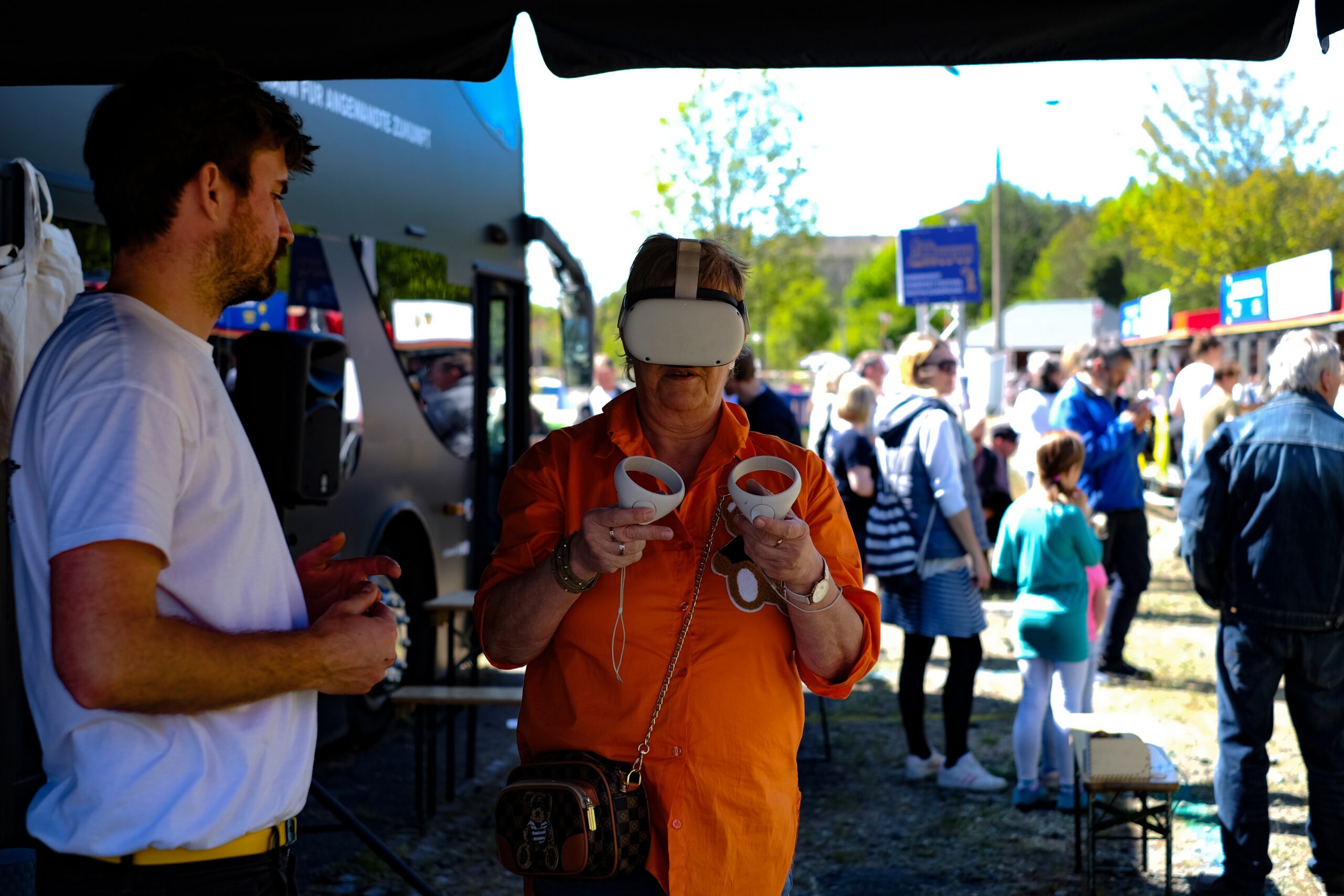 Eine Frau im orangenen Shirt probiert eine VR Brille aus