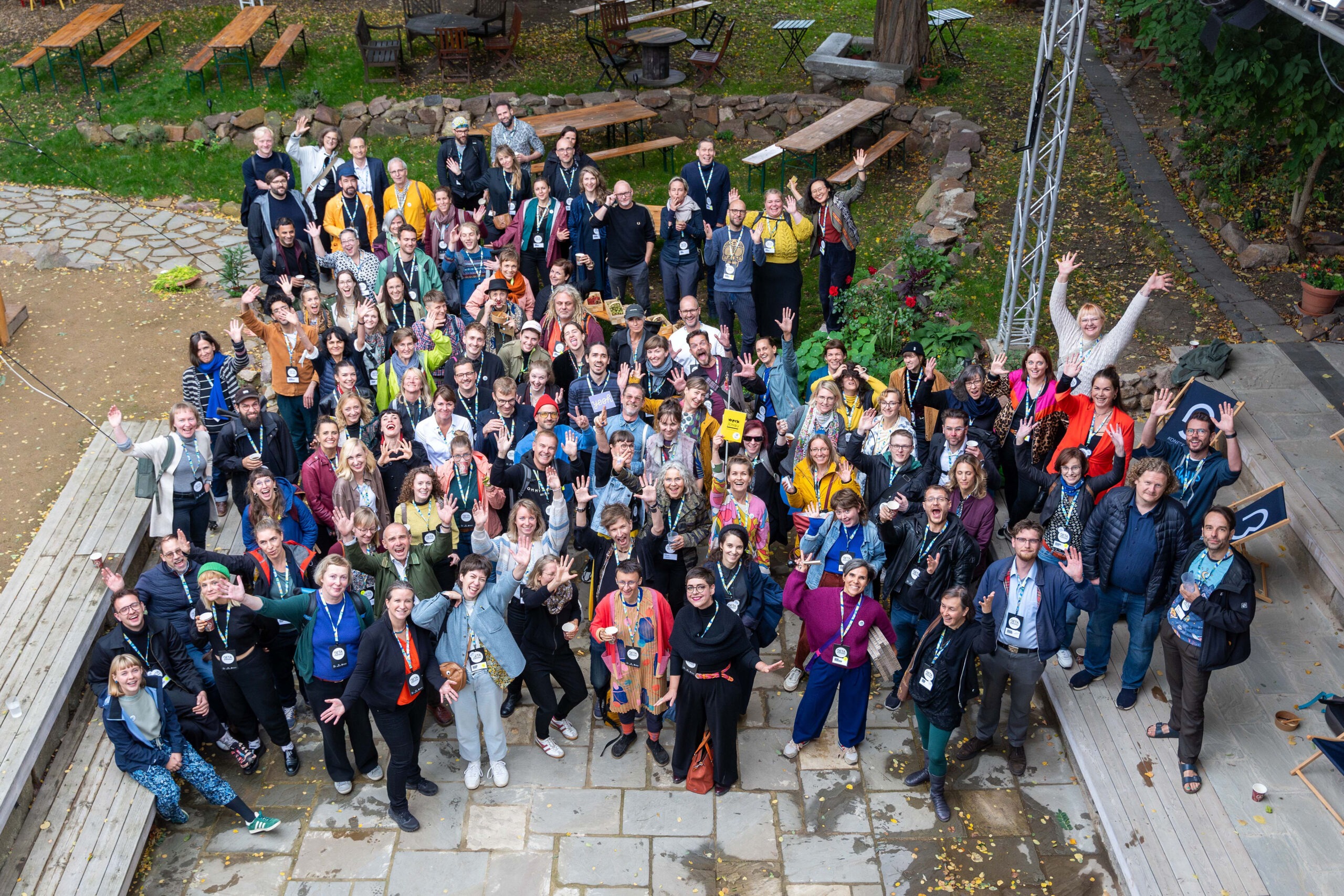 Gruppenfoto von ungefähr 150 Personen von oben fotografiert. Alle lachen oder ziehen eine Grimasse.