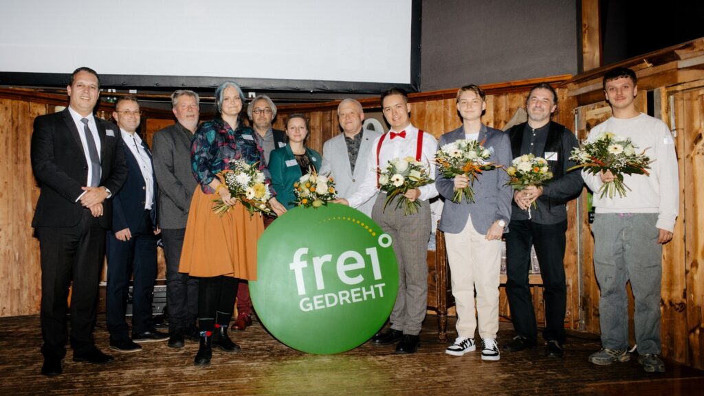 Gewinnerinnen und Jury auf einer Bühne, im Vordergrund das Logo des Wettbewerbs freiGEDREHT